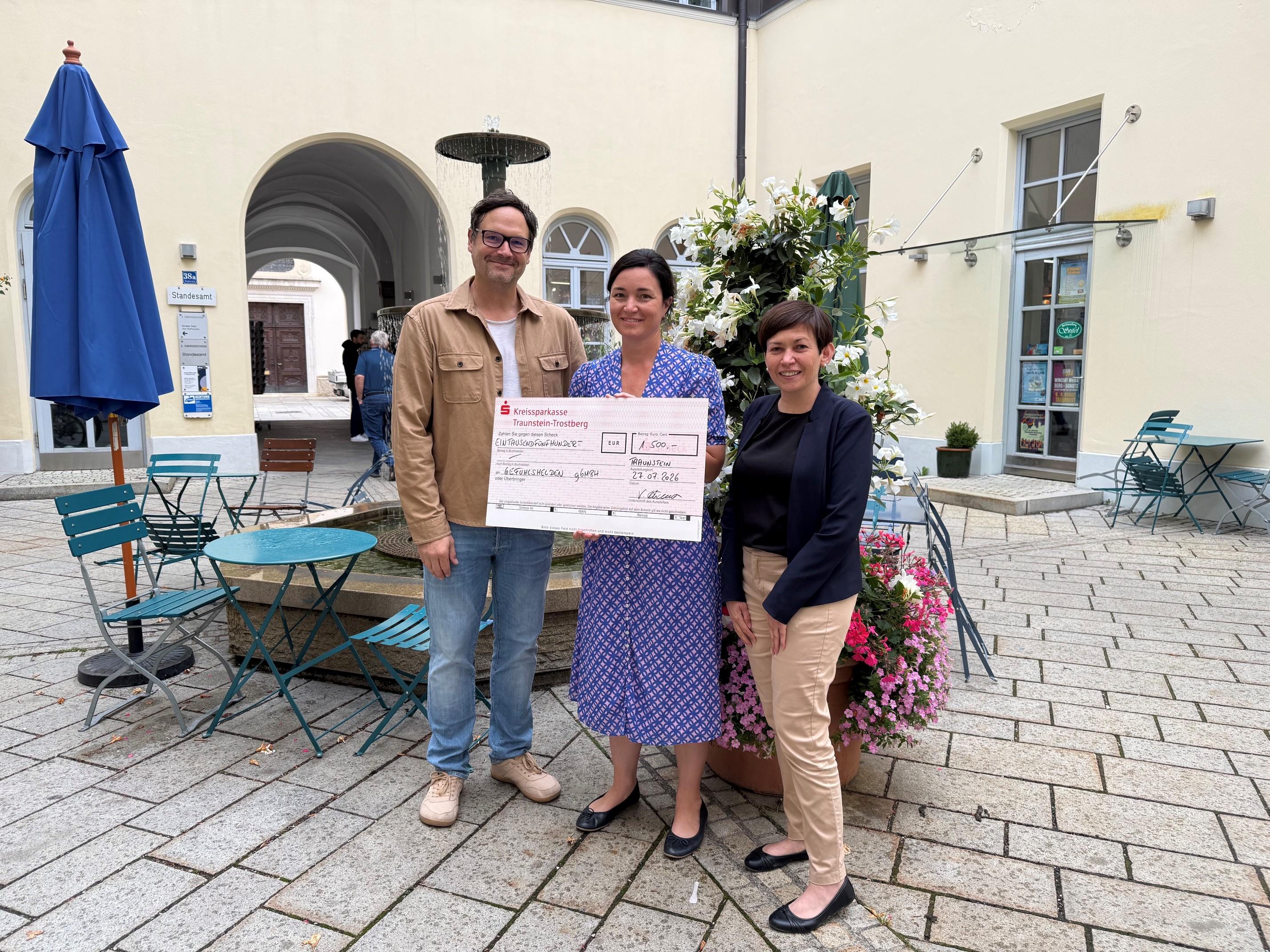 Im Brunnenhof des Traunsteiner Rathauses nahm Geschäftsführer Daniel Georg Stoklossa von Veronika Hümmer, Schirmherrin der Aktion „…die im Dunkeln sieht man nicht“ einen symbolischen Scheck in Höhe von 1.500 Euro entgegen. Auf dem Bild (von links): Geschäftsführer Daniel Georg Stoklossa, Schirmherrin Veronika Hümmer und Teresa Hain, Leiterin des Sachgebiets Familie, Bildung und Generationen im Rathaus. (© Große Kreisstadt Traunstein)