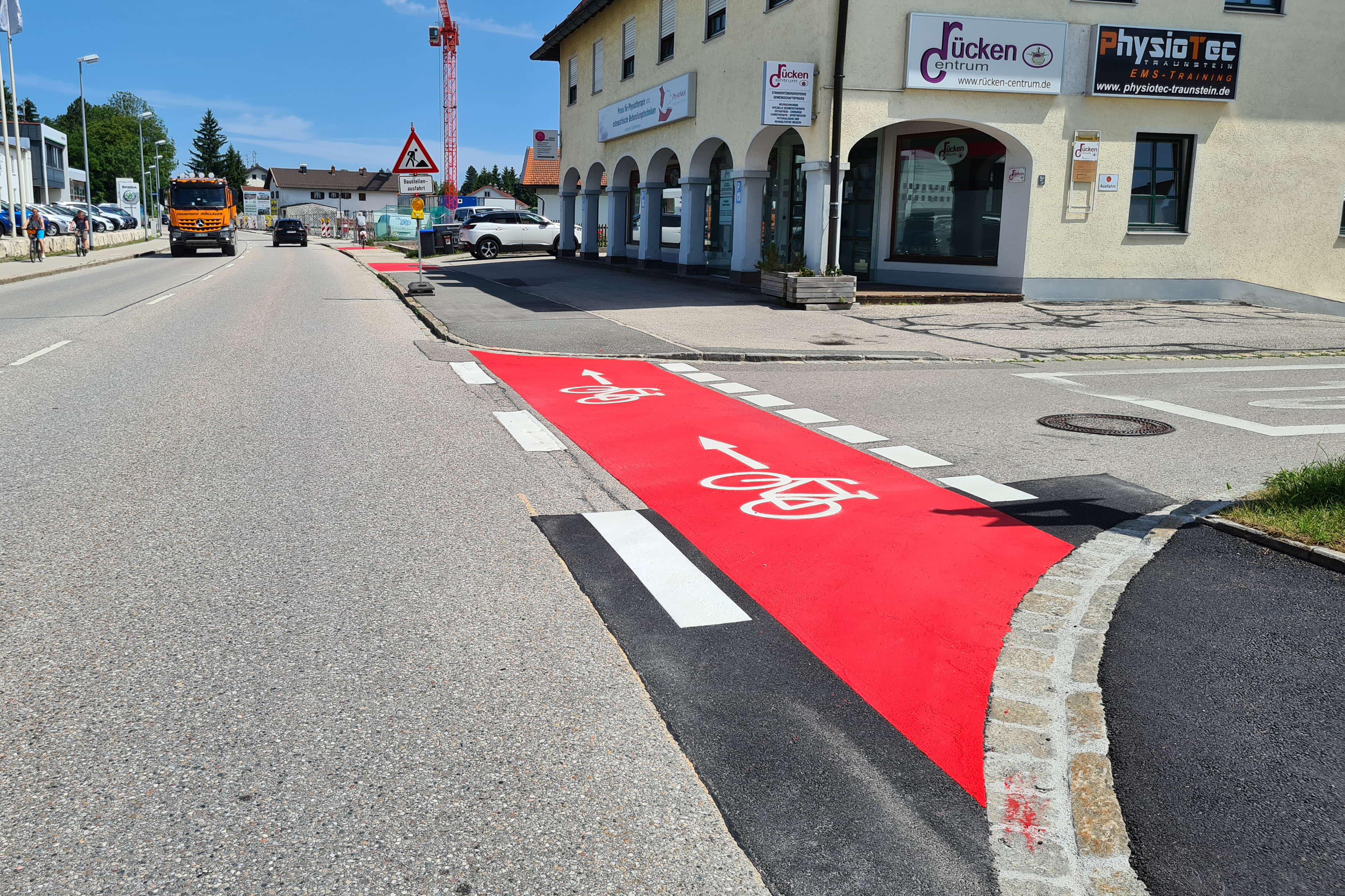 Auf der Chiemseestraße wurden die Rotmarkierungen der Radwege an Einmündungen aufgefrischt. An der Geßelestraße (Bild) wurde außerdem der Bordstein abgesenkt. Außerdem weisen nun an mehreren Stellen neue Fahrradpiktogramme mit Richtungspfeilen darauf hin, dass hier Fahrradfahrer unterwegs sind. (Bild © Carola Westermeier / Große Kreisstadt Traunstein)